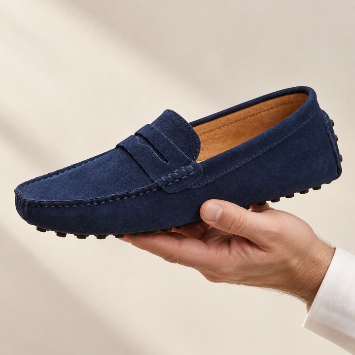 Lucca loafers in navy blue, held in a hand.