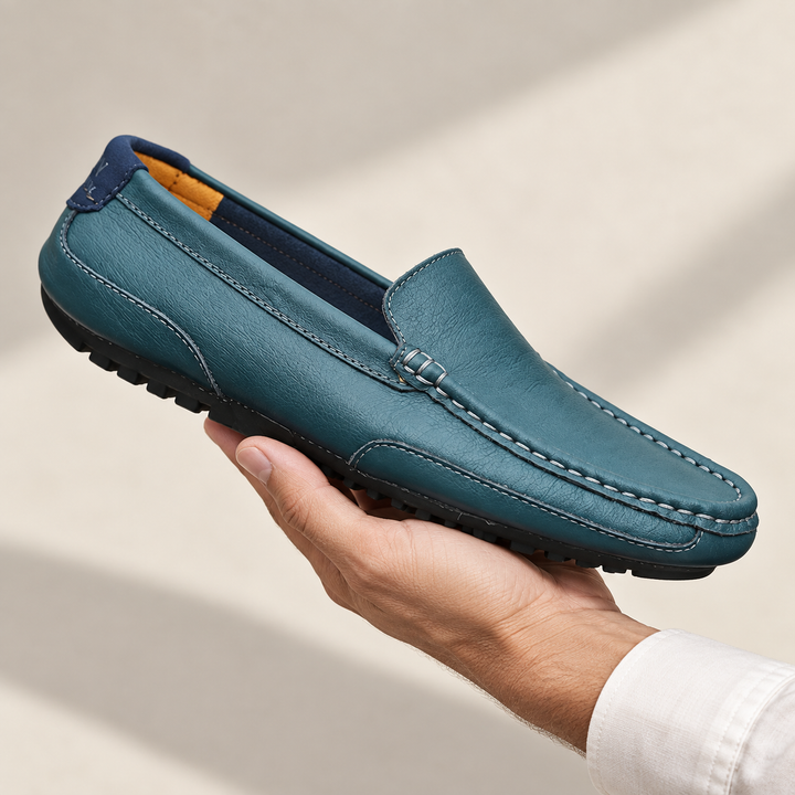 Matteo loafers in petrol blue, held in a hand.