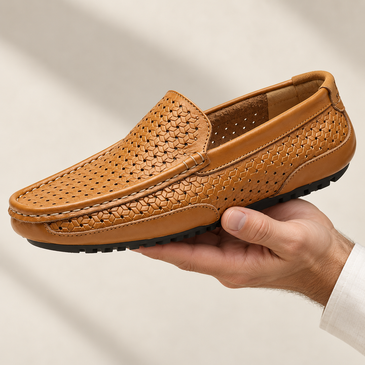 Ravello loafers in perforated tan, held in a hand.