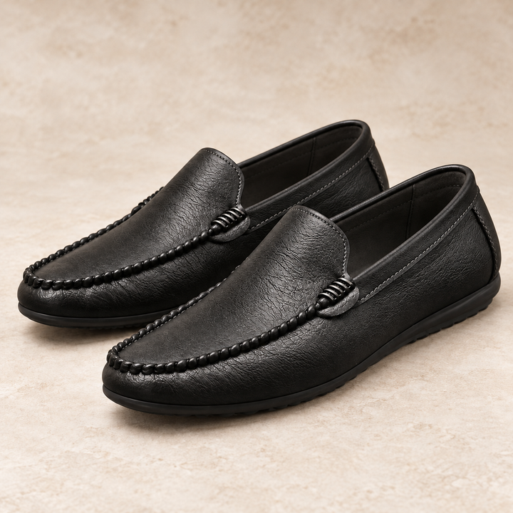 Ronan black moc-toe loafers with braided apron stitching and dark soles, photographed as a pair in a warm neutral studio.