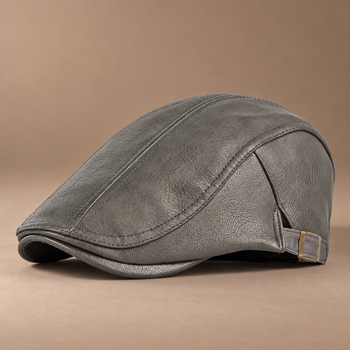 Heritage Leather Driving Cap in ash grey, photographed in a warm taupe studio