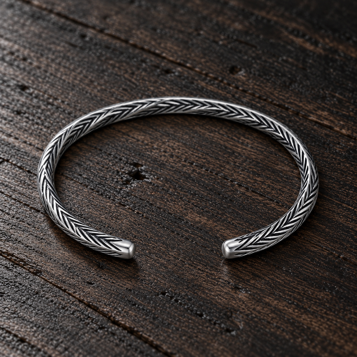 The Camden B-512S sterling silver engraved cuff resting flat on dark wood, with its open ends visible